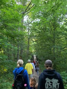 Activity participants walk towards a suspension bridge on a sunny summer morning.