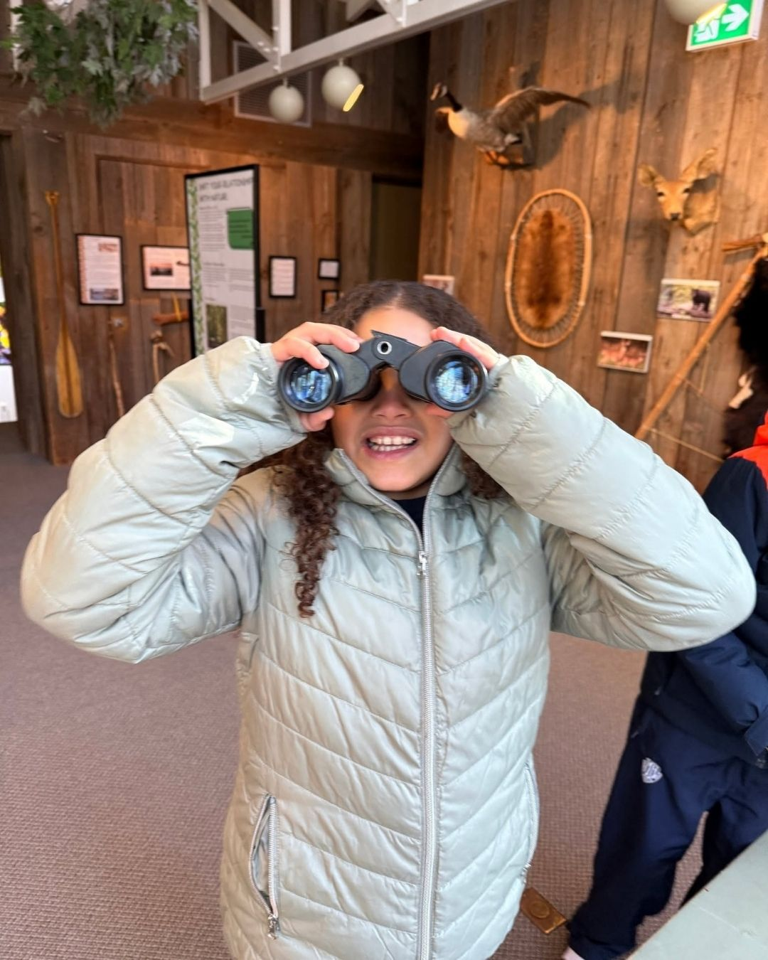 A young girl looks through binoculars.